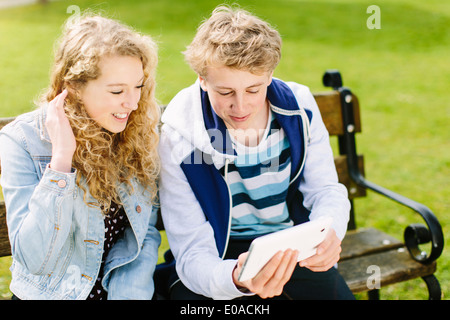 Frères et sœurs adolescents looking at digital tablet on bench Banque D'Images