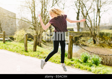 Teenage girl jumping mid air on rural road Banque D'Images