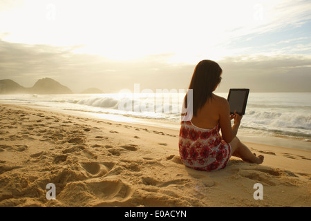 Mature Woman using digital tablet sur la plage de Copacabana, Rio de Janeiro, Brésil Banque D'Images