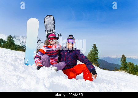 Couple assis dans masques de ski sur la neige Banque D'Images