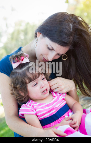 Mixed Race Mère pleurant Consoles sa petite fille à parc. Banque D'Images