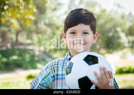 Jeune garçon jouant avec un ballon de football à l'extérieur dans le parc. Banque D'Images