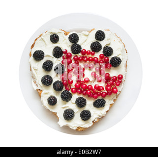 Gâteau en forme de coeur avec de la crème fouettée et les baies, isolé sur fond blanc Banque D'Images