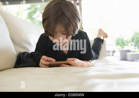 Jeune garçon couché sur le canapé en jouant sur un jeu vidéo Banque D'Images