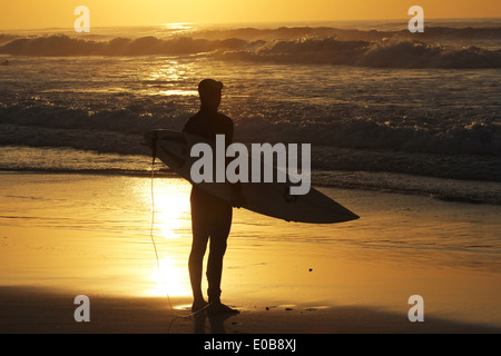 Surfer à Pacific Grove en Californie pendant un beau coucher du soleil s'apprête à aller faire du surf à bord et golden sun light sea Banque D'Images