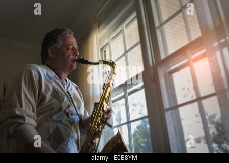 Homme mûr à la maison à jouer du saxophone Banque D'Images