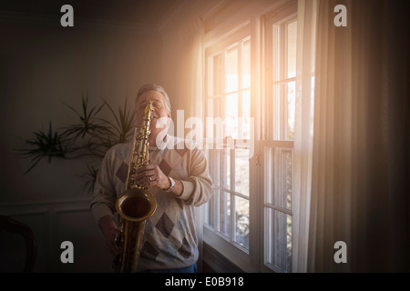 Homme mûr à la maison la pratique de saxophone Banque D'Images