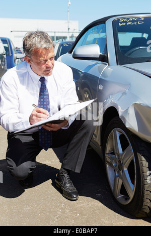 Loss Adjuster Inspecting Car impliqué dans un accident Banque D'Images