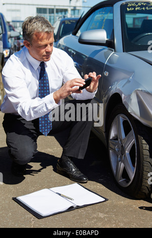 Loss Adjuster Inspecting Car impliqué dans un accident Banque D'Images