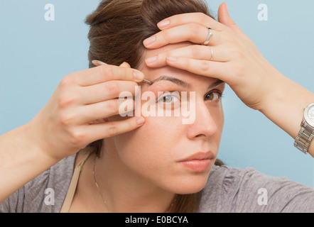 Une jeune femme épilation sourcils, Close up Banque D'Images