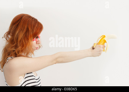 Superhero girl wearing mask avec fraises et bananes holding gun Banque D'Images