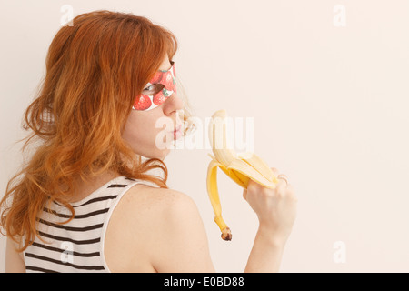 Superhero girl wearing mask avec fraises tenant un pistolet banane Banque D'Images