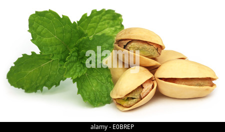 Les pistaches avec les feuilles de menthe verte sur fond blanc Banque D'Images