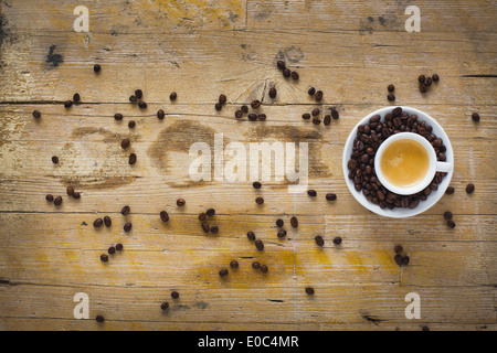 Une tasse de café entourée de grains de café Banque D'Images