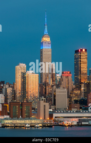 L'Empire State Building, au crépuscule, avec la lueur orange du ciel de l'ouest reflète dans les fenêtres des bâtiments. Banque D'Images