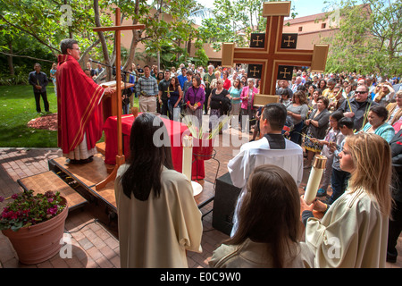 Le pasteur de l'Église catholique saint Timothée à Laguna Niguel, CA traite de paroissiens le Dimanche des Rameaux de l'église cour intérieure. Remarque les palmes, croix et les jeunes servants d'autel dans des robes. Banque D'Images