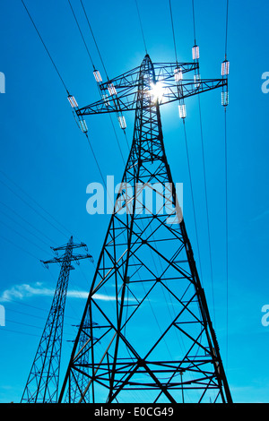 Le flux d'un mât de gestion haute tension avec le soleil et ciel bleu. L'approvisionnement énergétique en ligne d'alimentation électrique., der von Strommast Banque D'Images