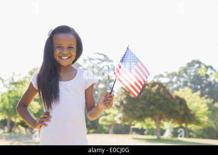 Little girl smiling at camera waving american flag Banque D'Images