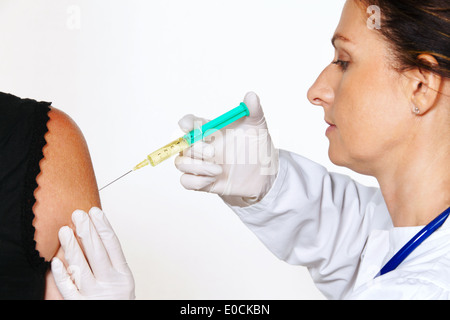 Jeune médecin inocule contre des maladies du patient et à l'influenza., Junger Arzt impft Frauenspezifische und gegen Patient Grippe. Banque D'Images