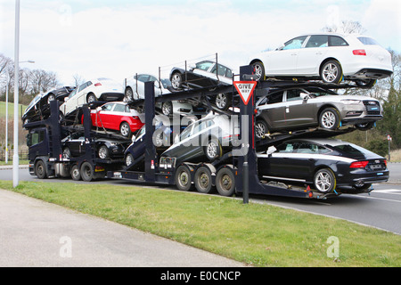 Une voiture transportant un chargement de nouvelles voitures Audi et voyager autour d'un rond-point à Coulsdon, Surrey, Angleterre Banque D'Images