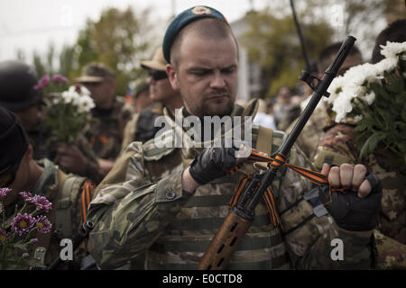 9 mai 2014 - Donetsk, Ukraine - un milicien armé de la République populaire de Donetsk forces d'autodéfense met un ruban de Saint-Georges, traditionnellement un symbole de lutte antifasciste, sur son fusil d'assaut au cours de la 9e de mai à Donetsk, les célébrations de la victoire de l'Est de l'Ukraine. Cette année, la parade, célébrant la victoire de l'Union soviétique sur l'Allemagne DANS LA SECONDE GUERRE MONDIALE, a eu lieu dans un contexte de tensions dans l'Est de l'Ukraine, où un mouvement de plus en plus pro-russe a occupé des dizaines de bâtiments du gouvernement et a l'intention de tenir un référendum afin de se séparer de l'autre du pays et peut-être rejoindre la Fédération de Russie Banque D'Images