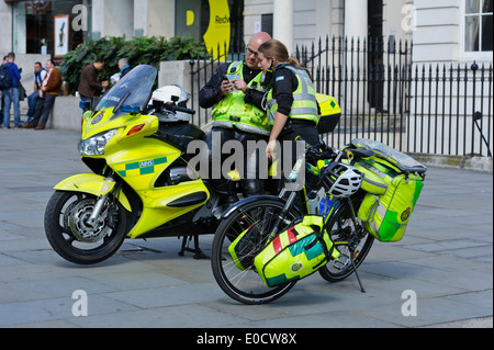 Deux techniciens médicaux d'envoyer des messages sur le téléphone par une moto à grande vitesse et une location dans la ville de Londres, Angleterre, Royaume-Uni. Banque D'Images