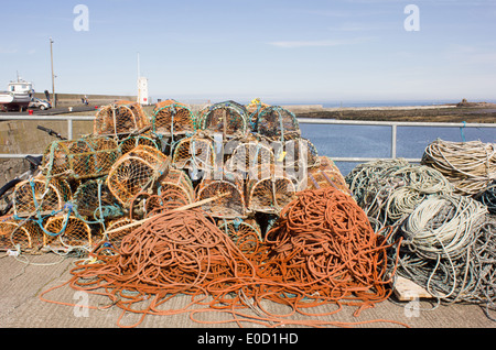 Des casiers à homard et cordes de pêche sur le quai au port de Seahouses, Northumberland, Angleterre Banque D'Images