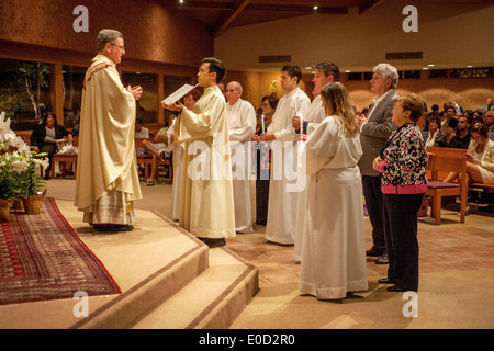 Le pasteur de l'Église catholique saint Timothée, Laguna Niguel, CA, se lit l'évangile à de nouveaux membres de la congrégation dans la nuit de leur baptême. Note des robes blanches et sponsors. Banque D'Images