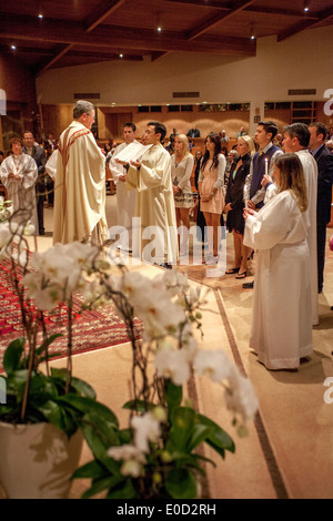 Le pasteur de l'Église catholique saint Timothée, Laguna Niguel, CA, se lit l'évangile à de nouveaux membres de la congrégation dans la nuit de leur baptême. Note des robes blanches et sponsors. Banque D'Images