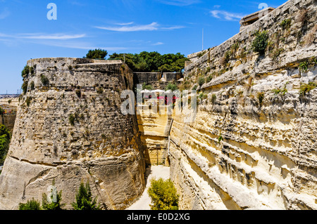 Les fortifications massives de St John's bastion et le mur rideau mal essuyé menant à la porte de la ville de La Valette, Malte Banque D'Images