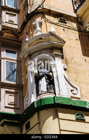 Un son réaliste statue de Saint Dominique avec un chien à ses pieds prêcher à partir d'une niche construite en haut d'un coin de rue, La Valette Banque D'Images