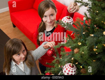 Sœurs (8-9, 10-11) decorating Christmas Tree Banque D'Images