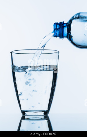 On verse de l'eau d'une bouteille dans un verre, photo symbolique pour l'eau potable, des besoins et de la consommation, aus einer Flasche Wasser wird Banque D'Images