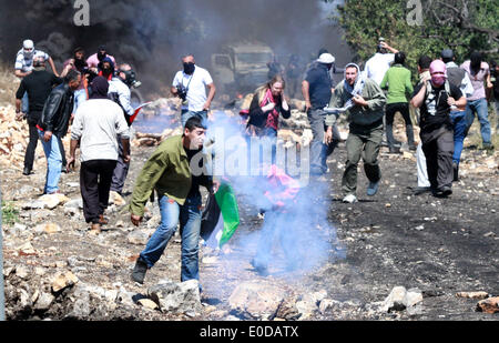 Naplouse. 9 mai, 2014. Des manifestants palestiniens fuient les gaz lacrymogènes lancés par les soldats israéliens au cours d'une manifestation contre l'expansion des colonies juives de Kufr Qaddoum village près de la ville cisjordanienne de Naplouse, le 9 mai 2014. © Ayman Nobani/Xinhua/Alamy Live News Banque D'Images