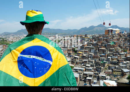 Fan de football brésilien au Brésil debout en face du pavillon de l'arrière-plan des bidonvilles favela à Rio de Janeiro Banque D'Images