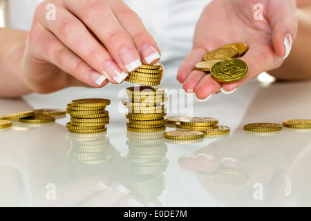 Les piles de pièces d'une femme. De l'argent à épargner pour l'avenir., Eine Frau stapelt Muenzen. Geld sparen fuer die Zukunft. Banque D'Images