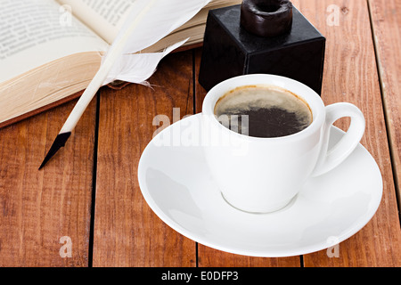 Tasse de café avec une plume d'encrier et livre sur fond de bois Banque D'Images