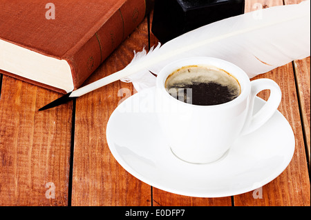 Tasse de café avec une plume d'encrier et livre sur fond de bois Banque D'Images