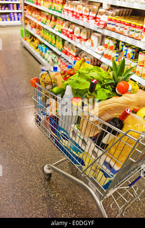 Un panier est d'une façon d'un supermarché entre les étagères., Ein Einkaufswagen steht einem von Supermarktes Gang Banque D'Images