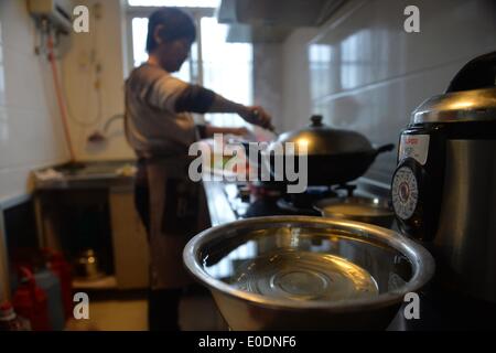 Dalian, province de Jiangsu. 10 mai, 2014. Un résident local cuisiniers à l'eau de puits réalisés dans les zones d'uptown Dalian, Chine de l'est de la province de Jiangsu, le 10 mai 2014. L'approvisionnement en eau de Jingjiang reprend le vendredi après avoir été suspendu pendant 7 heures, en raison de la qualité de l'eau anormale trouvé dans la rivière Yangtze, source d'eau. Cependant, certaines zones d'habitation se heurtent toujours au problème de pénurie d'eau. © Shen Peng/Xinhua/Alamy Live News Banque D'Images