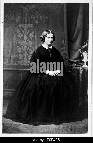 Portrait en noir et blanc d'une femme assise, pris dans un style vintage. La photographie représente les techniques de photographie de mode et de portrait du début du XXe siècle, avec un accent sur la simplicité et l'élégance. Banque D'Images