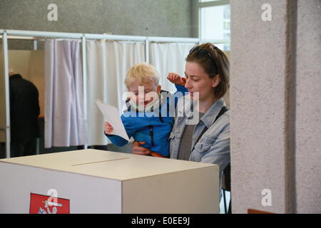 Vilnius, Lituanie. Le 11 mai, 2014. Une femme jette son vote avec son bébé dans un bureau de vote de Vilnius, en Lituanie, le 11 mai 2014. Environ 2,5 millions de lituaniens se sont rendus aux urnes dimanche pour élire un président de 7 candidats. Credit : Bu Peng/Xinhua/Alamy Live News Banque D'Images