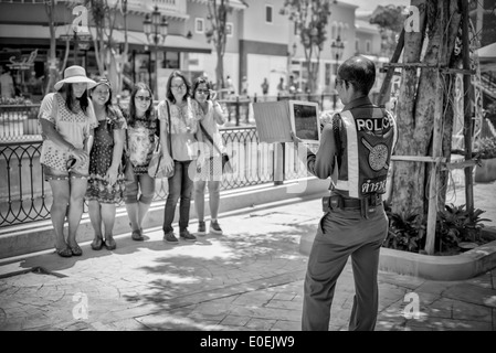 Le policier thaïlandais aide le groupe touristique local en prenant sa photo sur un iPad comprimé. Thaïlande S. E. Asie Photographie noir et blanc Banque D'Images