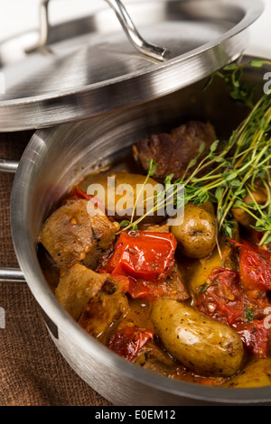 Rôti chaud avec la langue et les légumes dans la casserole avec couvercle métallique sur serviette marron Banque D'Images