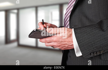 Un homme d'écrire un message avec un stylet sur un appareil électronique. Banque D'Images