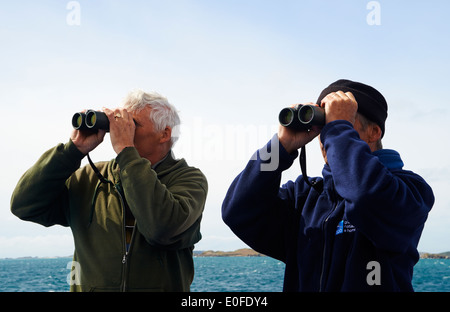 Deux hommes personnes de RSPB avec des jumelles à regarder les oiseaux sur le Scillonian III ferry boat trip d'Isles of Scilly, Scillies, Cornwall en Avril Banque D'Images