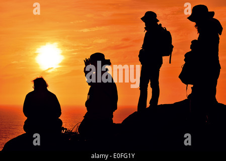 L'Espagne, la Galice : pèlerins de Saint James en regardant le coucher du soleil à pittoresque Cap Finisterra Banque D'Images