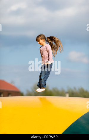 Girl sauter de haut en bas sur le château gonflable. Banque D'Images