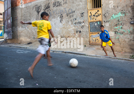 Deux garçons brésilien jouant au football de rue dans une favela de Rio de Janeiro, en maillots de football brésilien Banque D'Images