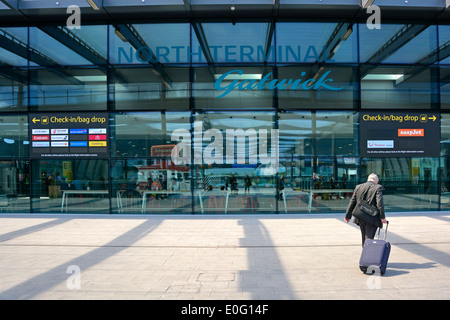 Voyageur à marcher en direction de l'enregistrement à l'aéroport de Londres Gatwick North Terminal Banque D'Images